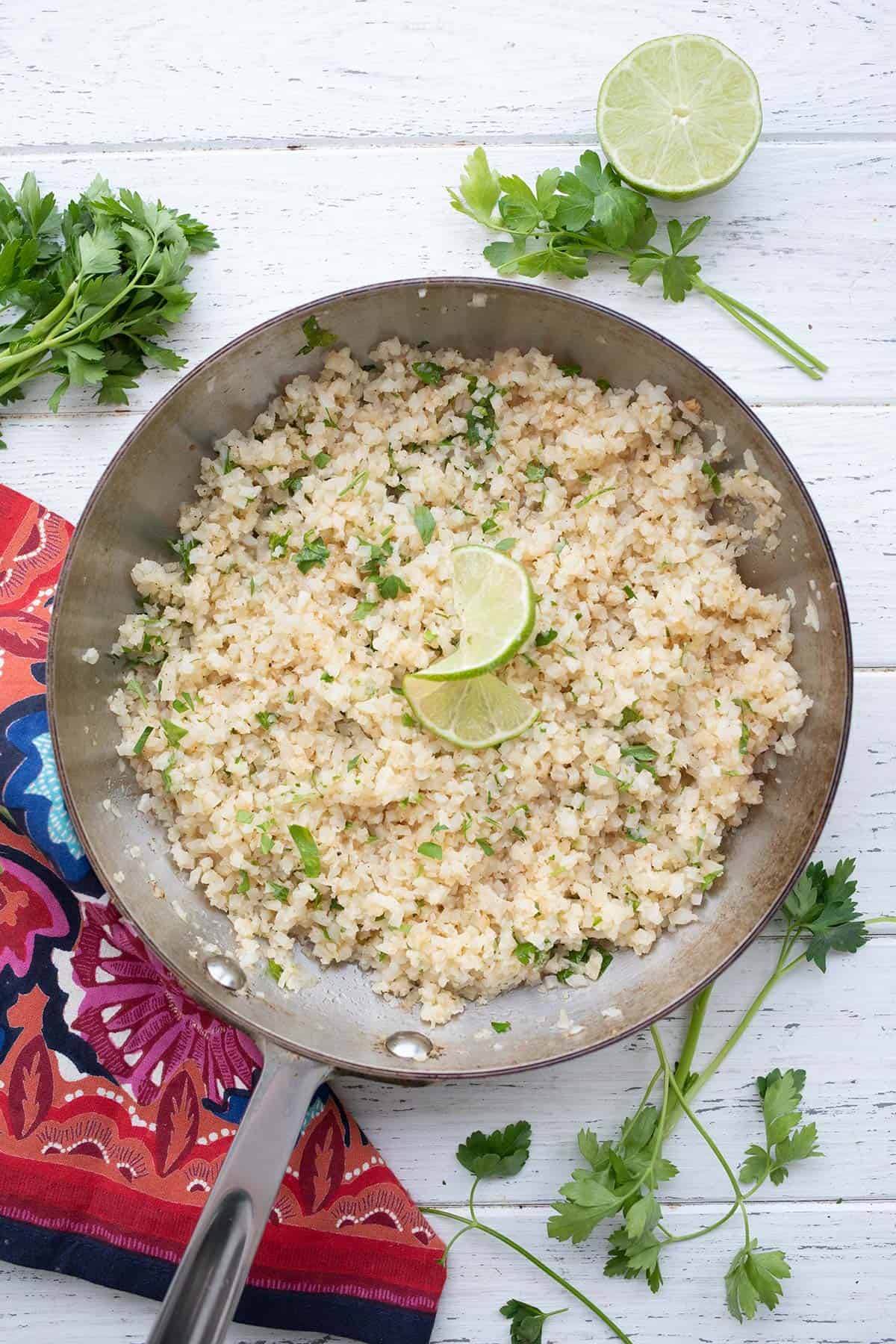 Top down image of Cilantro Lime Cauliflower Rice in a skillet on a white wooden table.