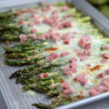 Baked Asparagus with Ham and Cheese on a metal baking sheet.