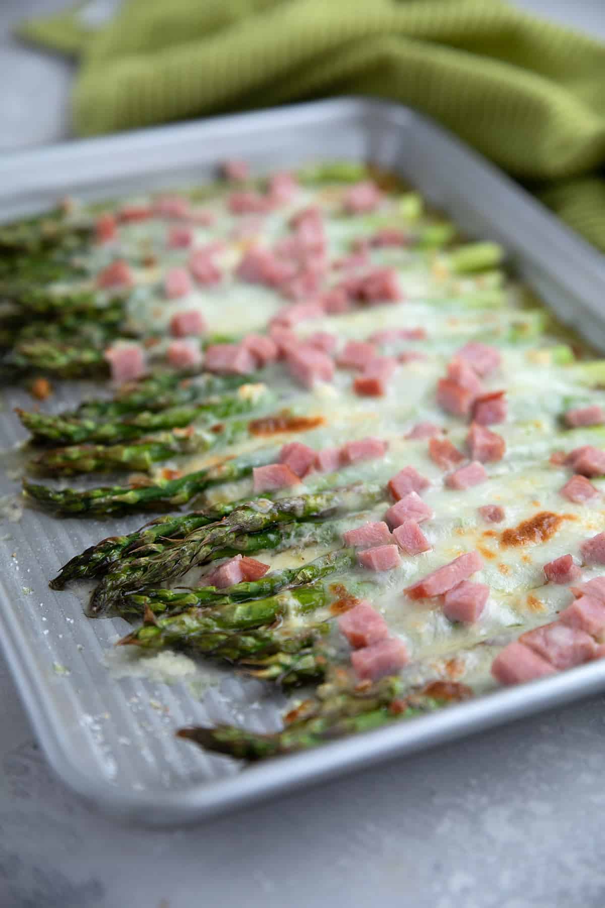 Baked Asparagus with Ham and Cheese on a metal baking sheet.