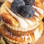 Close up shot of two Keto Cinnamon Roll Cheesecakes in a stack with blueberries on top.