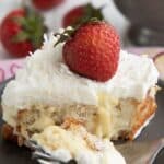 Close up shot of a slice of Keto Coconut Cream Poke Cake on a gray plate with a forkful in front.