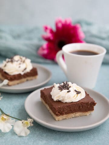 Two Keto French Silk Pie Bars on gray dessert plates with a cup of coffee.