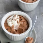 Two cups of Keto Chocolate Mousse on a gray concrete table.