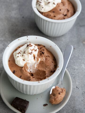 Two cups of Keto Chocolate Mousse on a gray concrete table.