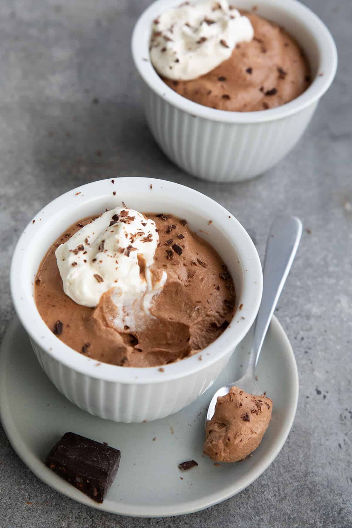 Two cups of Keto Chocolate Mousse on a gray concrete table.