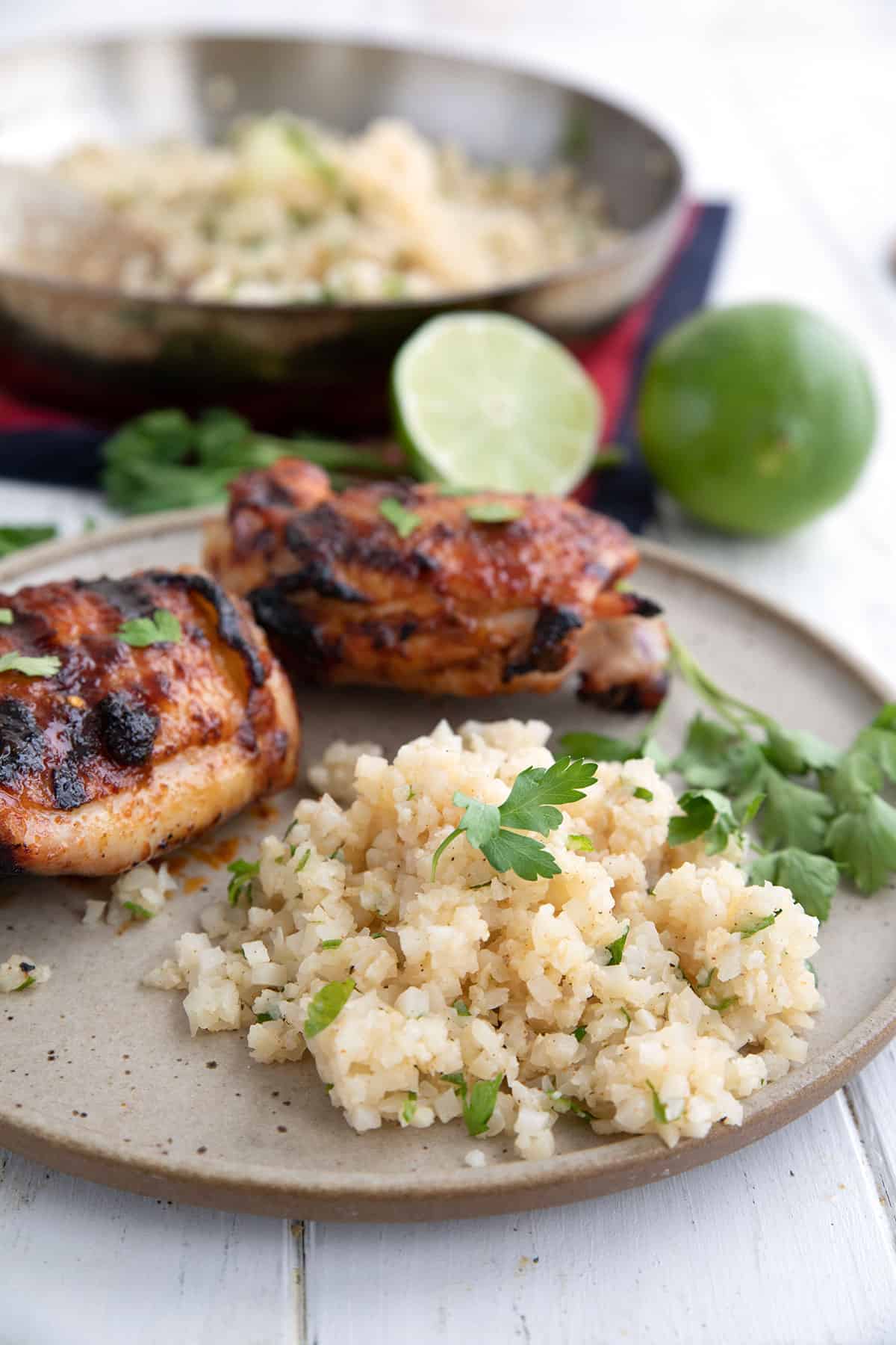 Cilantro Lime Cauliflower Rice on a stoneware pate with grilled chicken thighs.