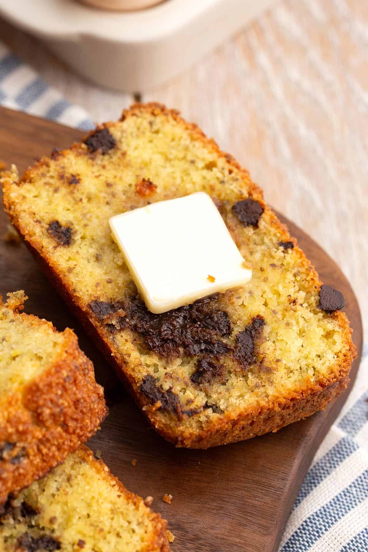 Close up shot of a slice of keto banana bread with a pat of butter on top.