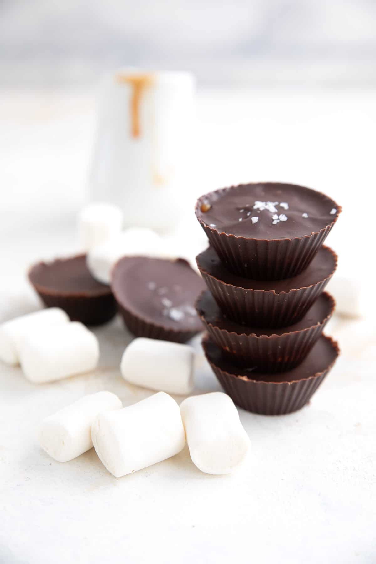 Keto Chocolate Cups in a stack, surrounded by sugar free marshmallows.