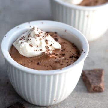 Two white dessert cups filled with creamy keto chocolate mousse.