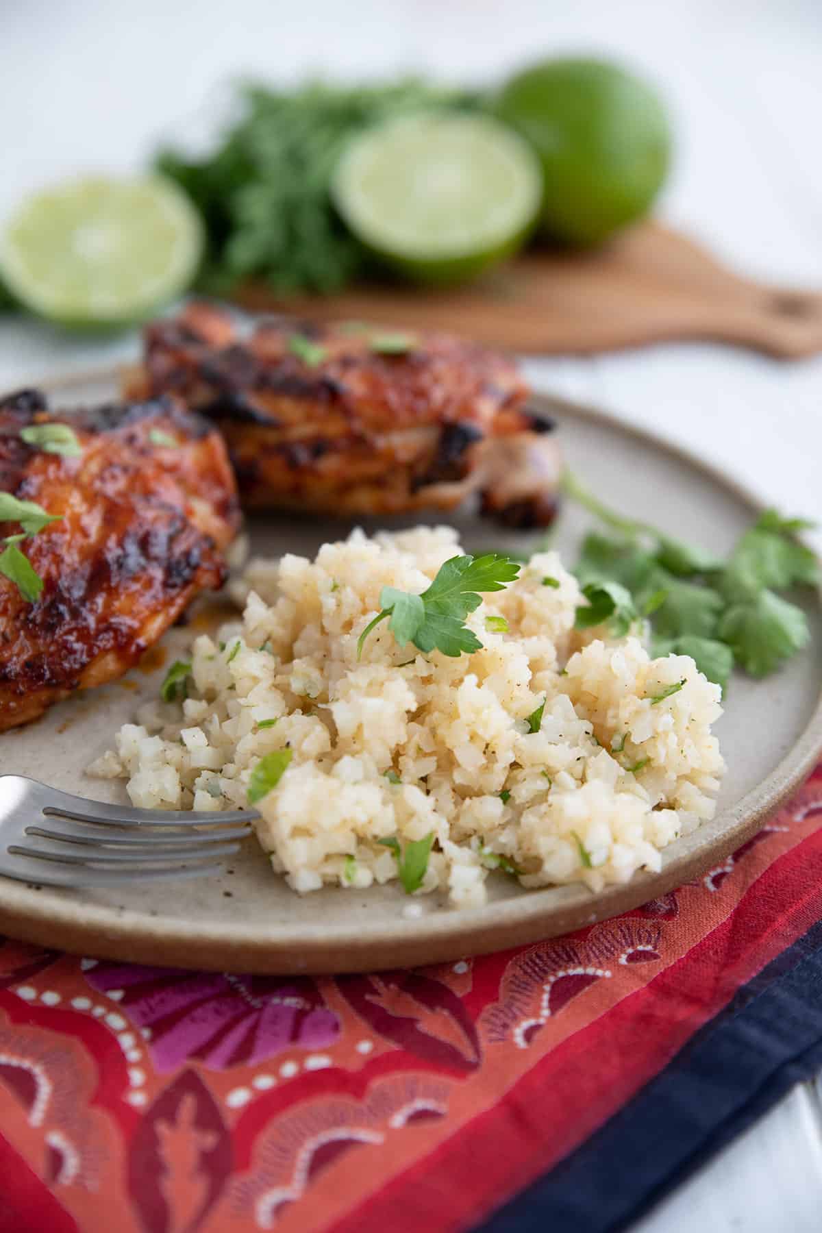 A serving of Cilantro Lime Cauliflower Rice on a plate with chicken.