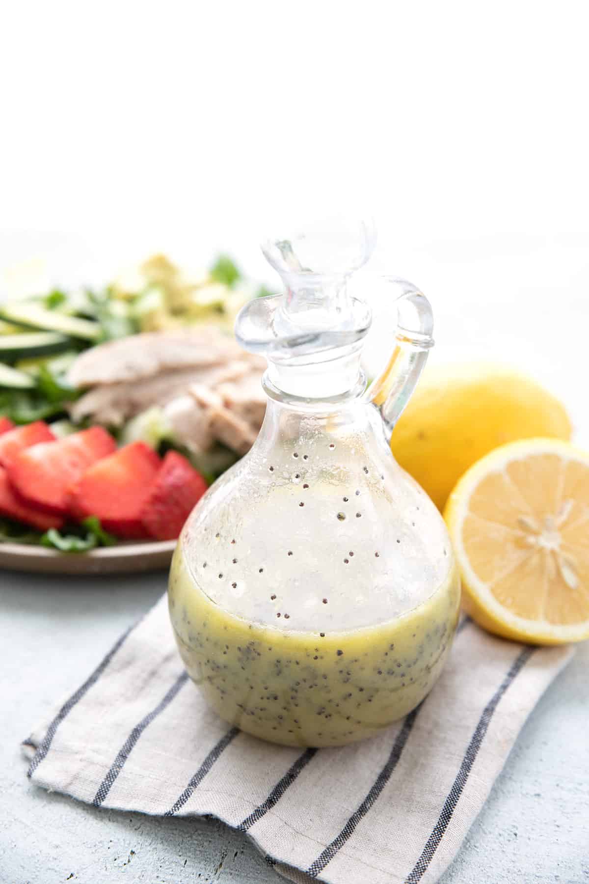Keto Lemon Poppy Seed Dressing on a striped napkin with lemons and salad in the background.