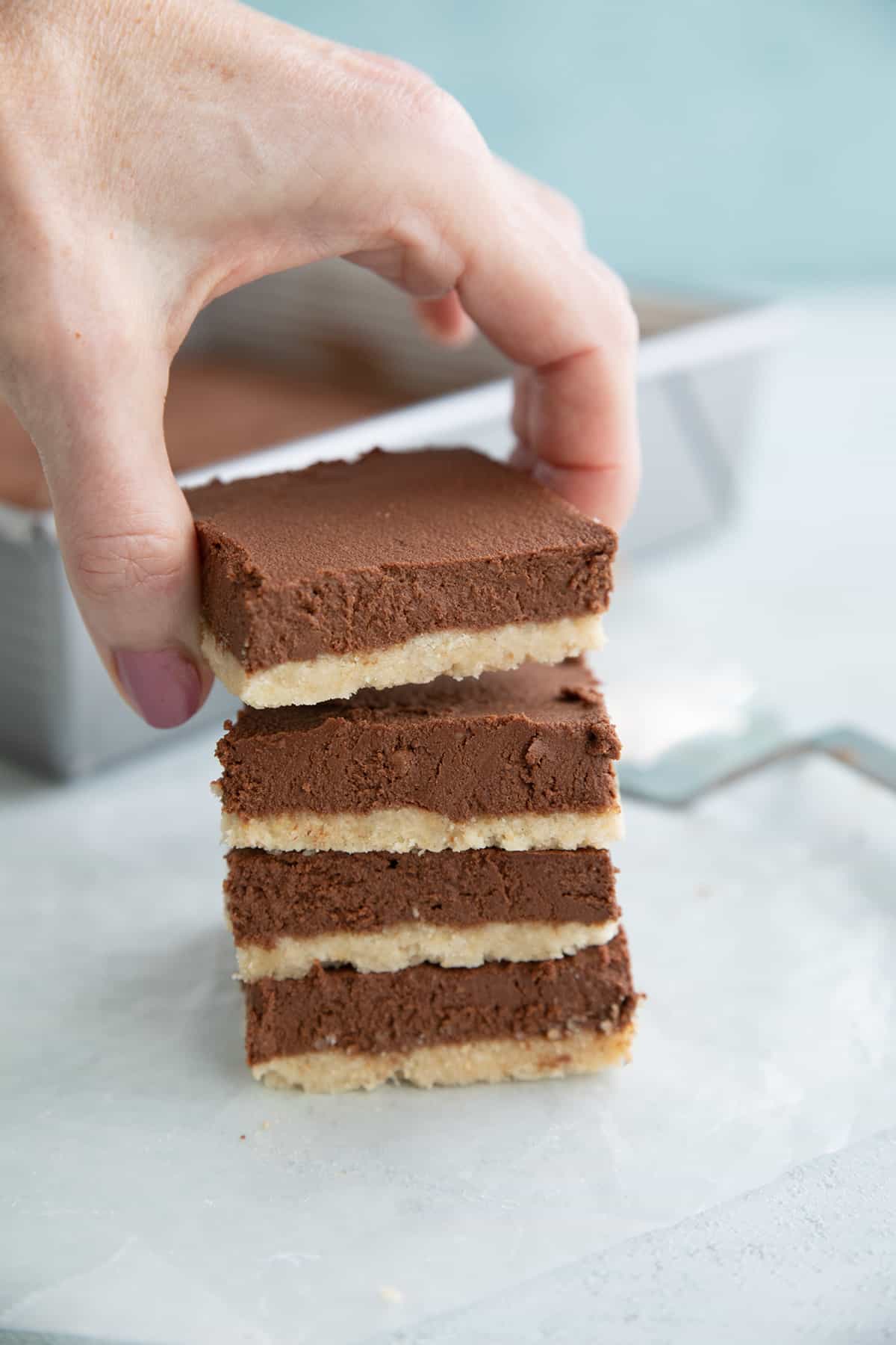 A stack of French Silk Pie Bars with a hand lifting off the top one.
