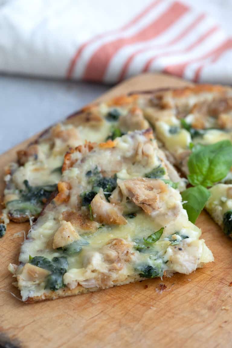 A slice of Keto Chicken Alfredo Pizza on a cutting board.