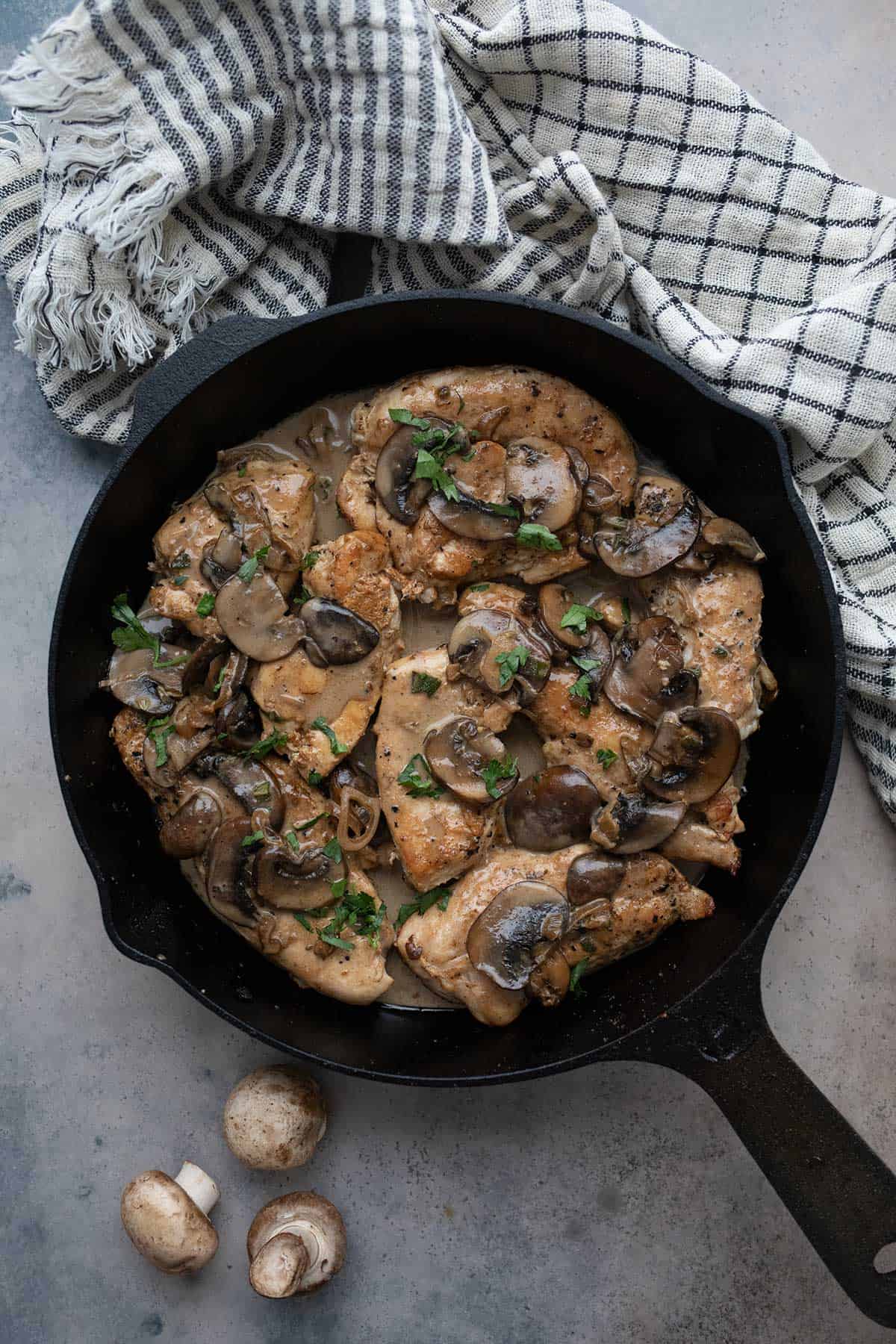 Top down image of Keto Chicken Marsala in a cast iron pan on a concrete table.