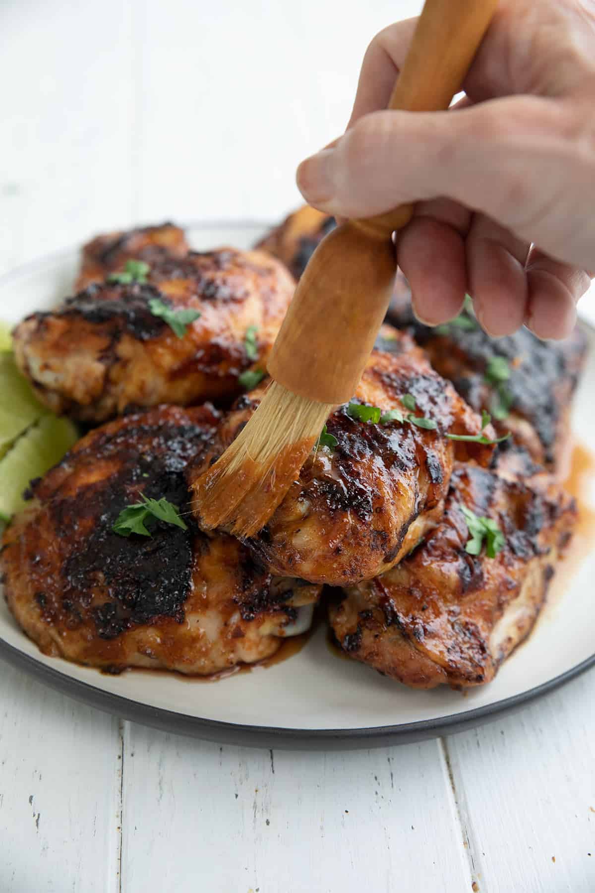 Chipotle lime marinade being brushed over grilled chicken thighs.