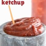 Titled Pinterest image of homemade keto ketchup in a marble bowl with a small wooden spoon.