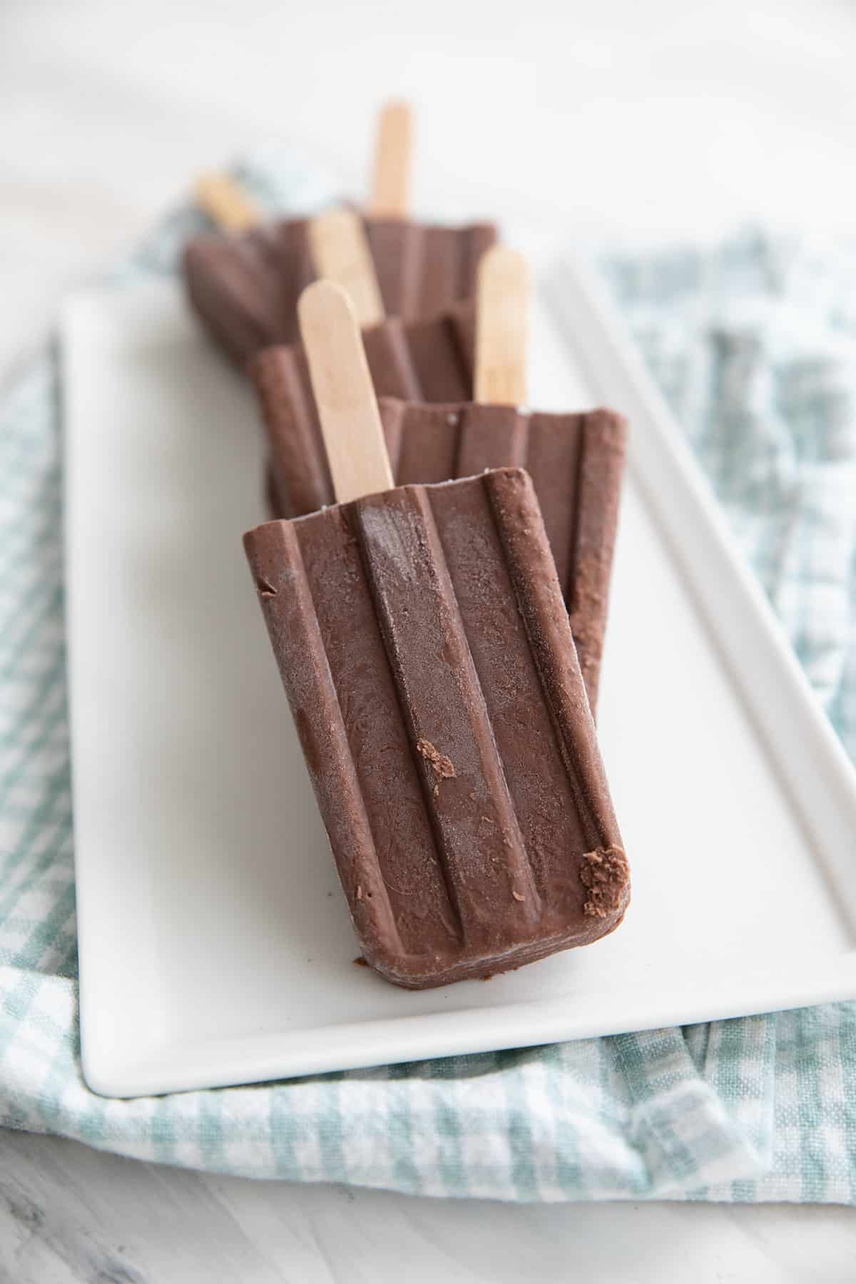 Keto chocolate popsicles lined up on a white tray.