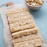 A pan of white chocolate macadamia keto protein bars on a cutting board, cut into slices.