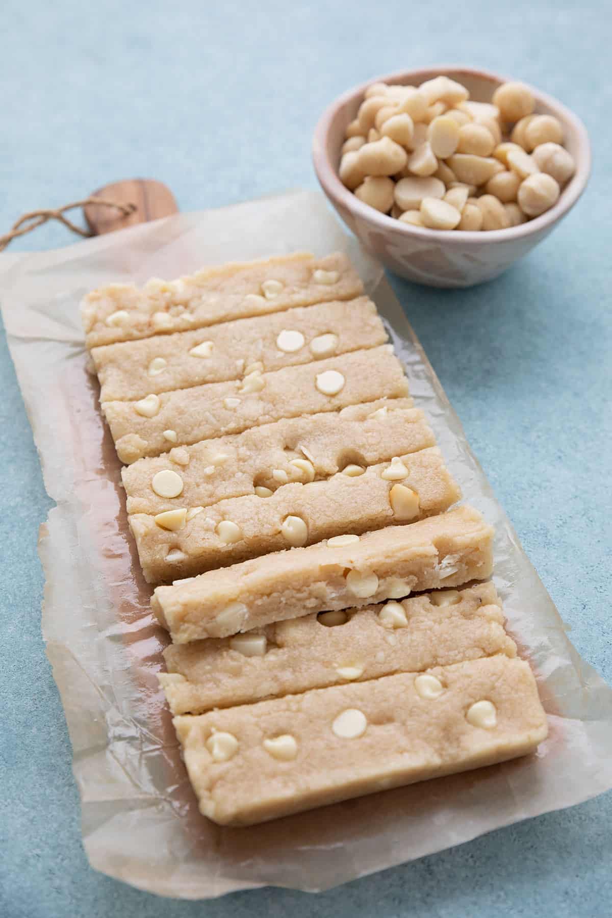 A pan of white chocolate macadamia keto protein bars on a cutting board, cut into slices.