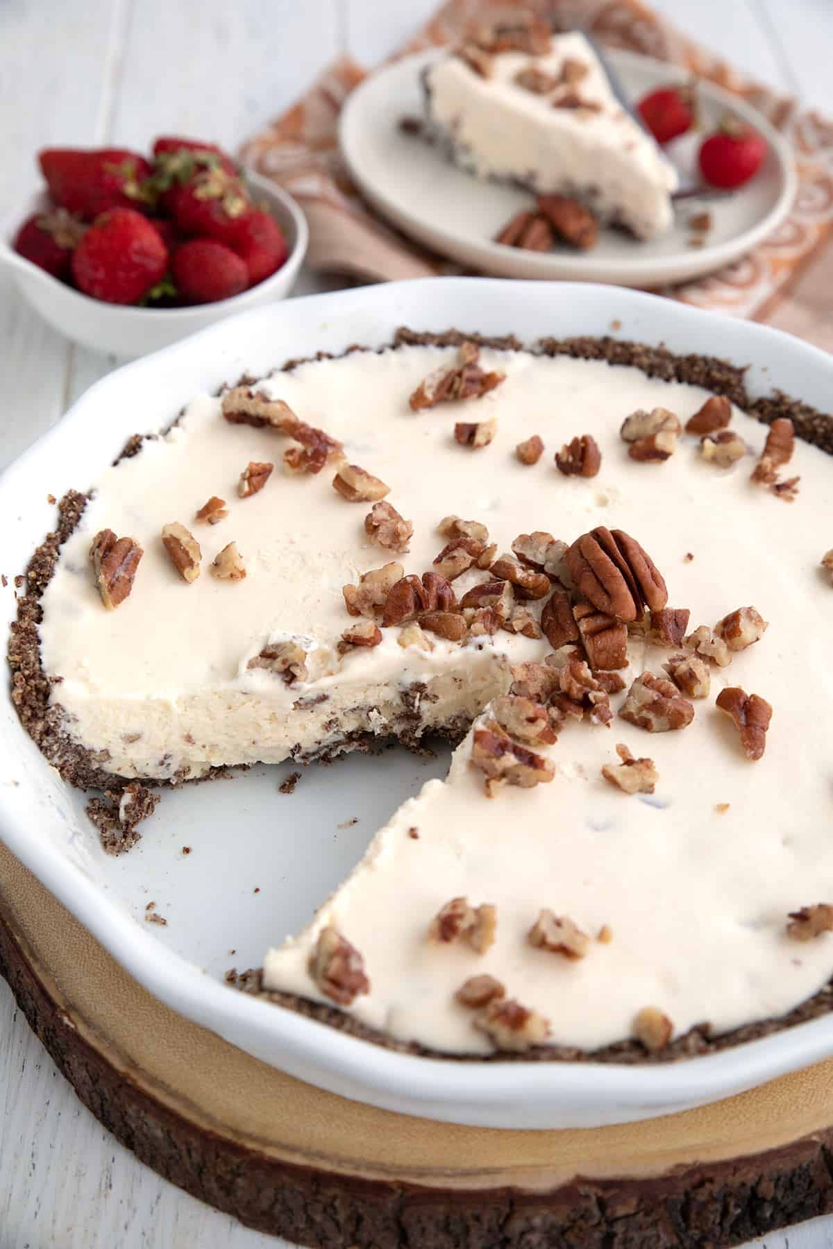 Keto Butter Pecan Ice Cream Pie in a white pie plate with a slice cut out of it.