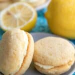 Two keto lemon sandwich cookies on a gray plate over a teal patterned napkin.