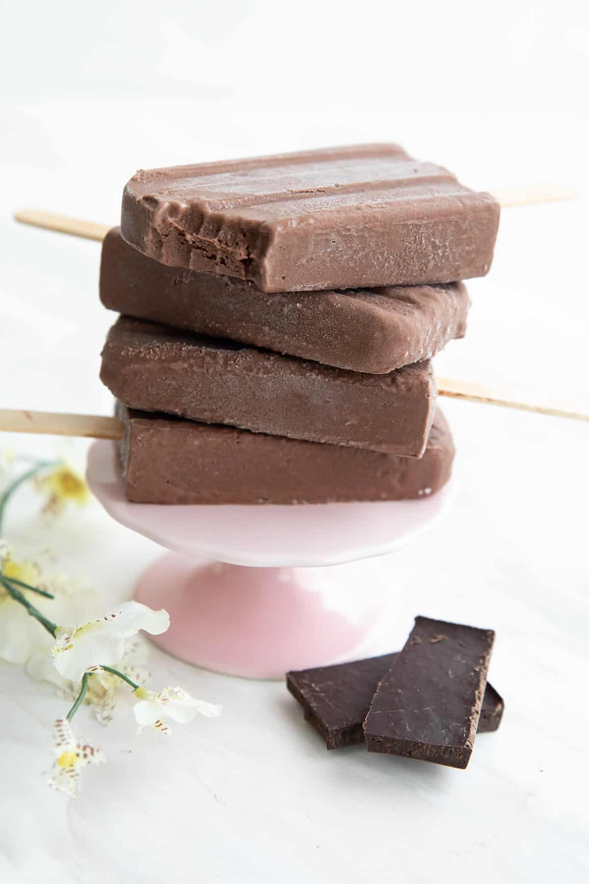 A stack of Sugar Free Fudge Pops on a pink cake stand, with a bite taken out of the top one.