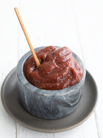 Sugar Free Ketchup piled up in a gray marble bowl with a small wooden spoon sticking out.