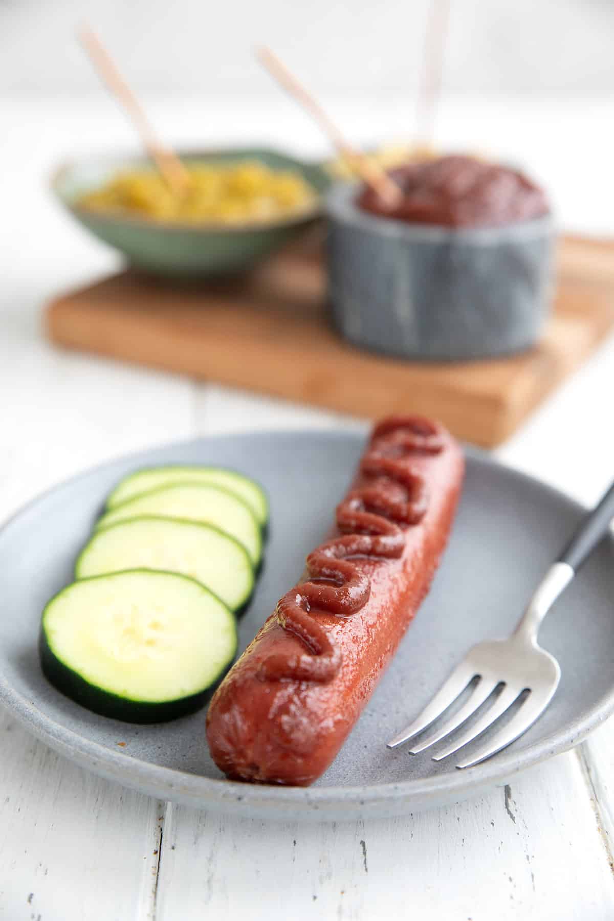 A hot dog on a plate with a drizzle of keto ketchup on top.