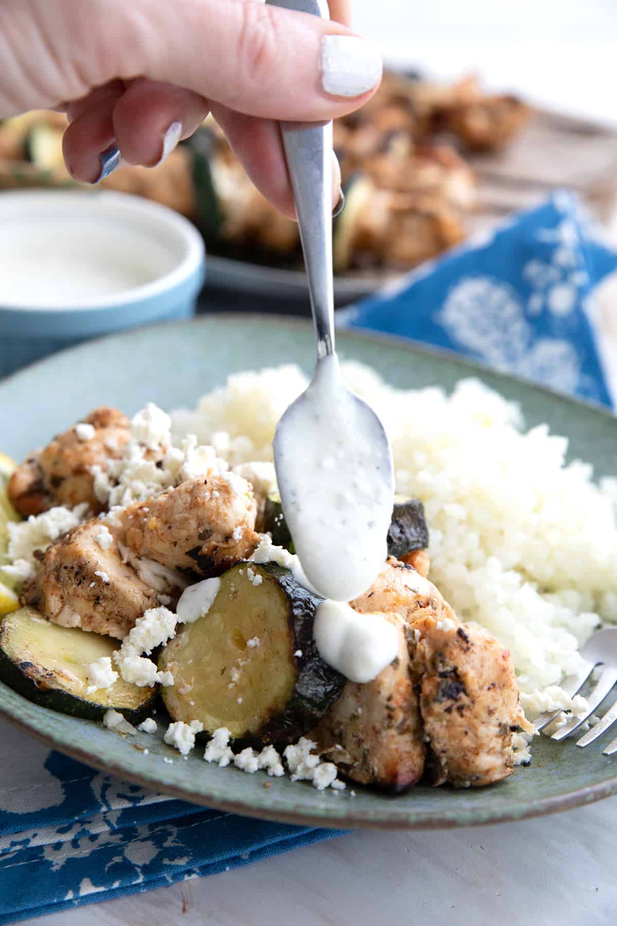 Feta dressing being drizzled over Chicken Souvlaki.