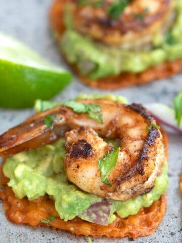 Close up shot of spicy shrimp and guacamole on a cheese crisp.