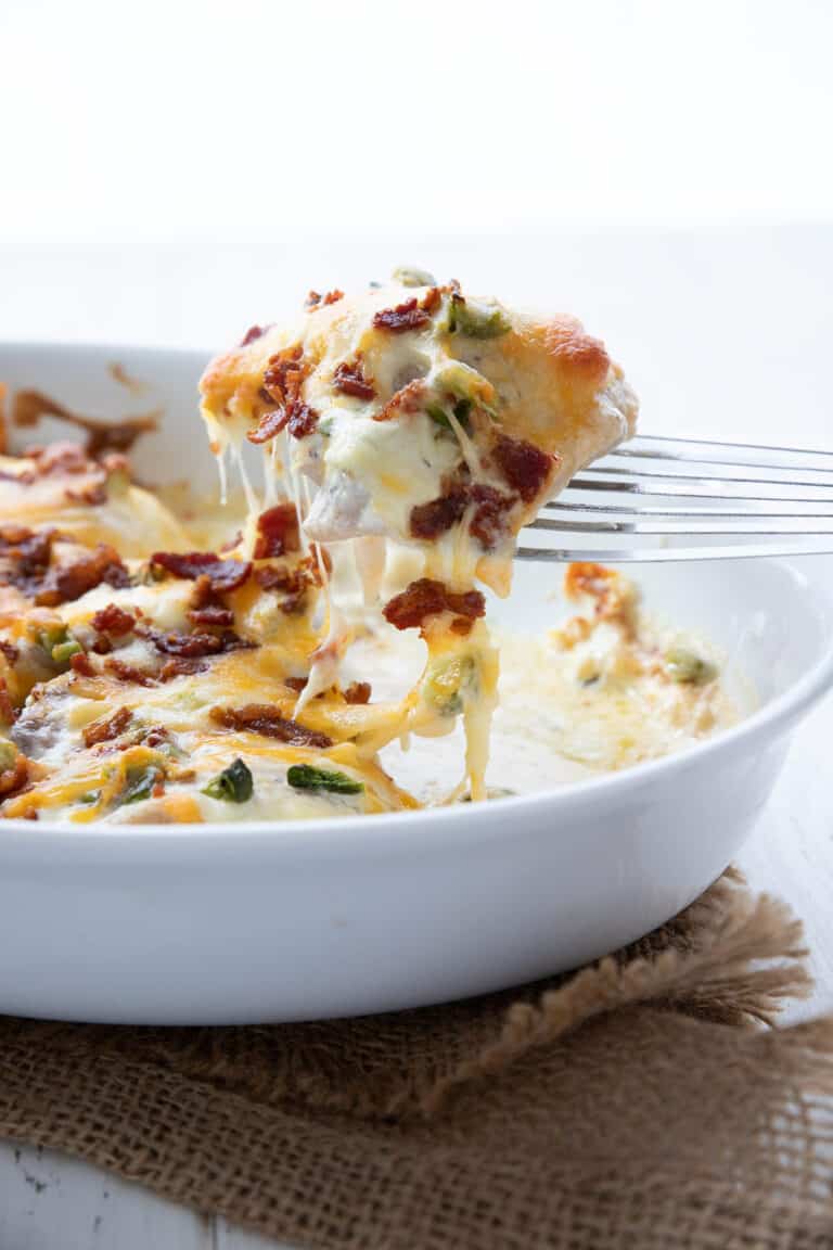 A spatula lifting a serving of Jalapeño Popper Chicken out of the baking dish.