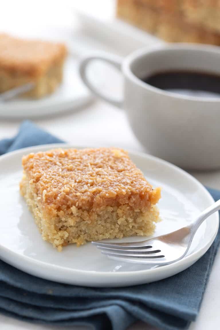 Keto Caramel Coconut Cake on a white plate with a fork.