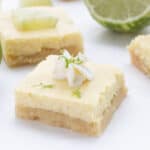 Close up shot of a keto key lime bar with whipped cream and lime zest on top.