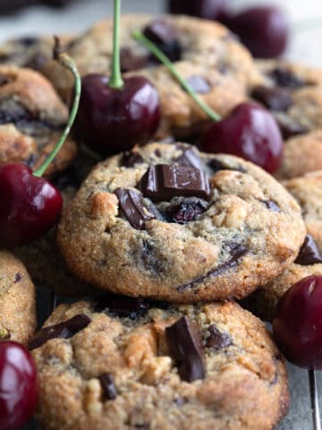 Close up shot of a pile of Cherry Chocolate Chunk Cookies on a cooling rack.