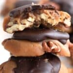 Titled image of a stack of keto pecan turtle candies on a white table, with a bite taken out of the top one.