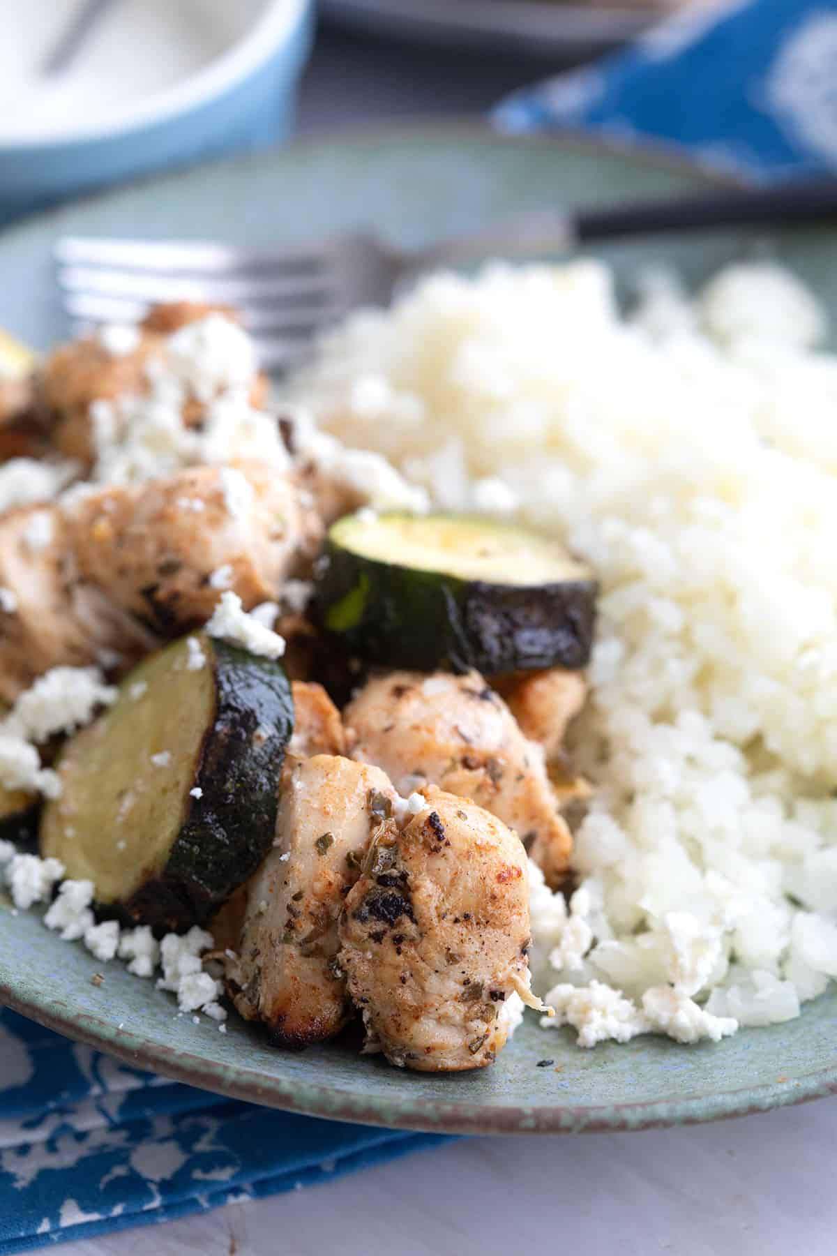 Close up shot of grilled chicken souvlaki on a plate with cauliflower rice.