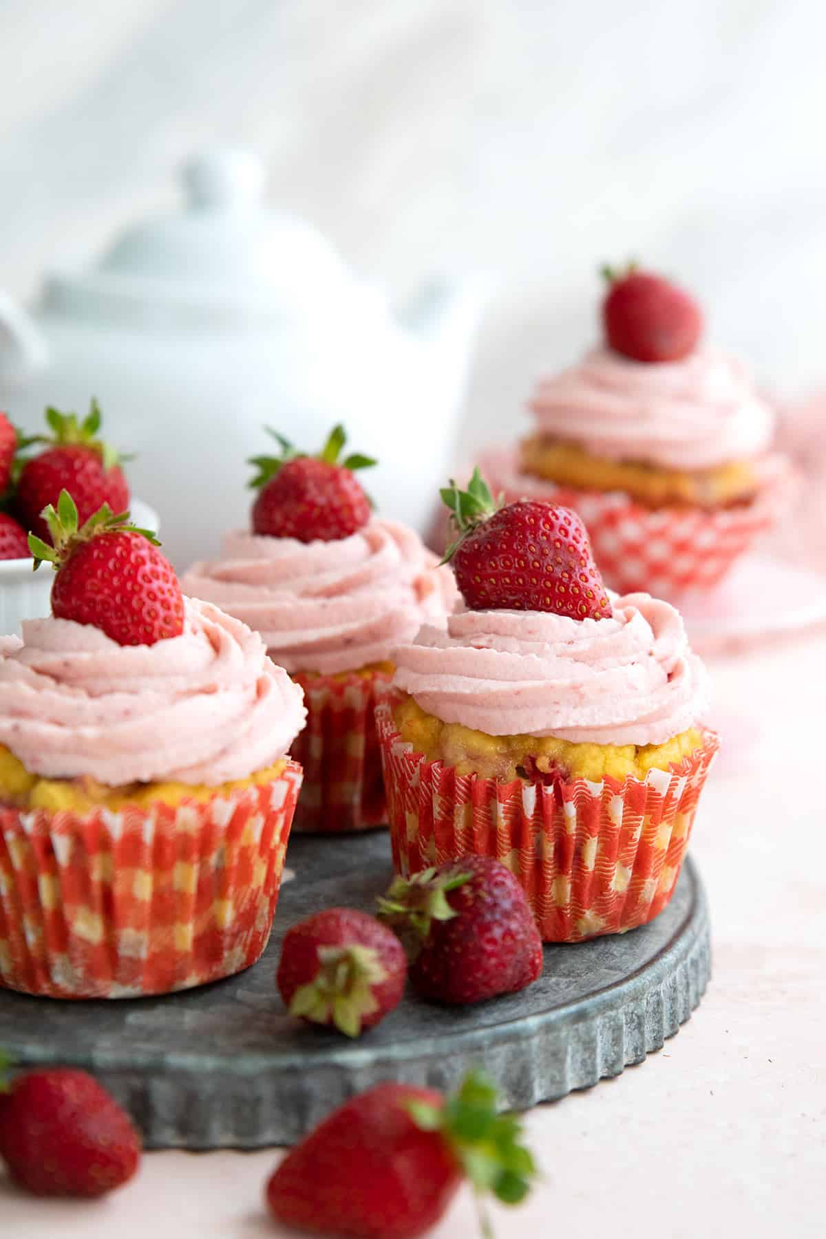 Keto Strawberry Cupcakes on a metal tray with strawberries strewn around.