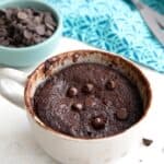 Easy keto protein mug cake in a coffee mug with chocolate chips on the table.