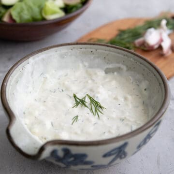 Feta Dressing iin a gray bowl in front of a bowl of salad.