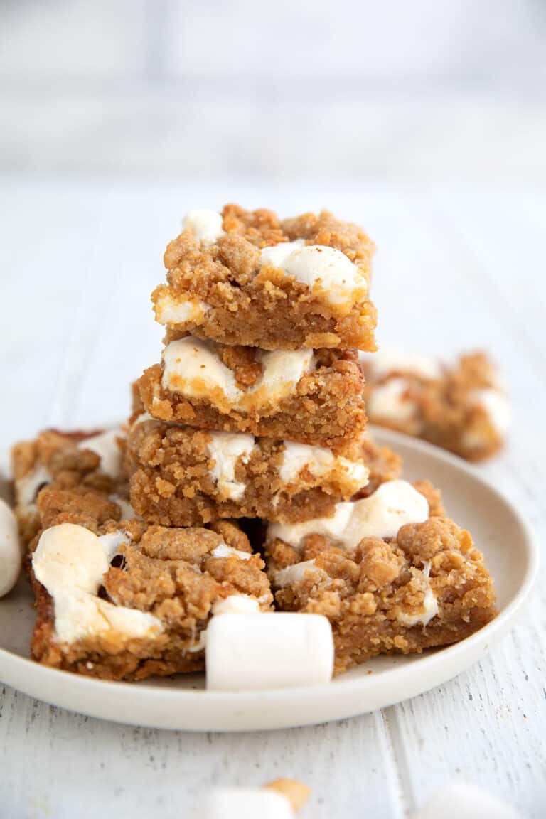 A stack of Keto Fluffernutter Bars on a white plate on a white wooden table.