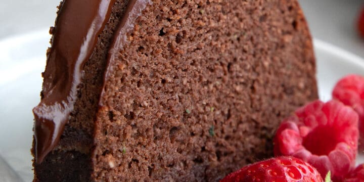 A slice of Keto Chocolate Zucchini Cake on a white plate with fresh berries.