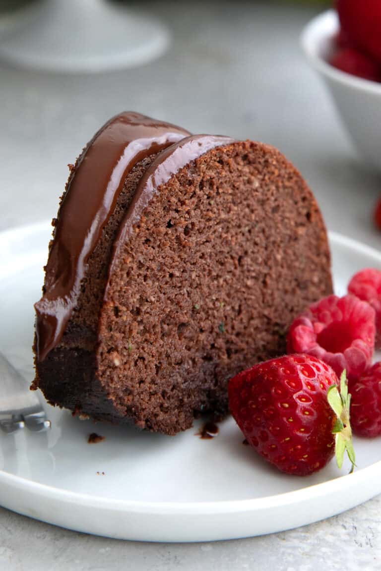 A slice of Keto Chocolate Zucchini Cake on a white plate with fresh berries.