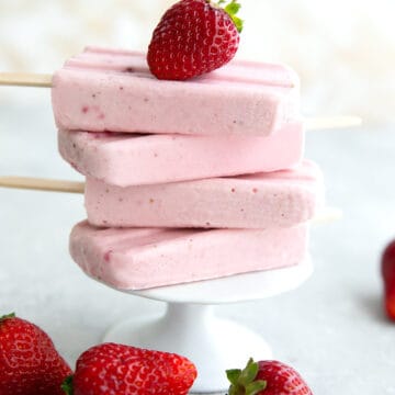A stack of strawberry keto popsicles on a white cupcake stand, with a strawberry on top.