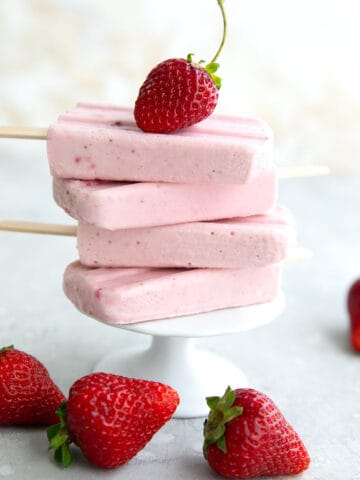 A stack of strawberry keto popsicles on a white cupcake stand, with a strawberry on top.