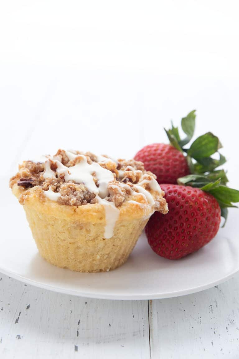 A coffee cake keto muffin on a white plate with strawberries.