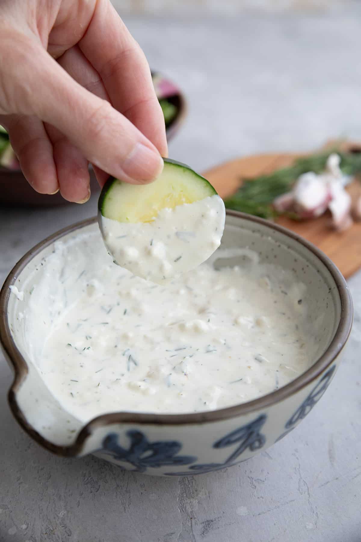 A hand dipping cucumber into Feta Dressing.