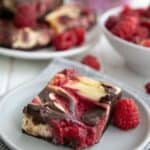 Titled image of a keto raspberry cheesecake brownie on a gray plate.