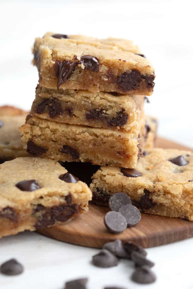 Gooey keto blondies piled up on a cutting boards.