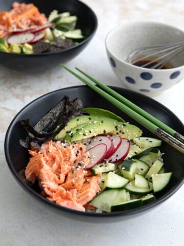Two Keto Sushi Bowls in black bowls on a concrete table.