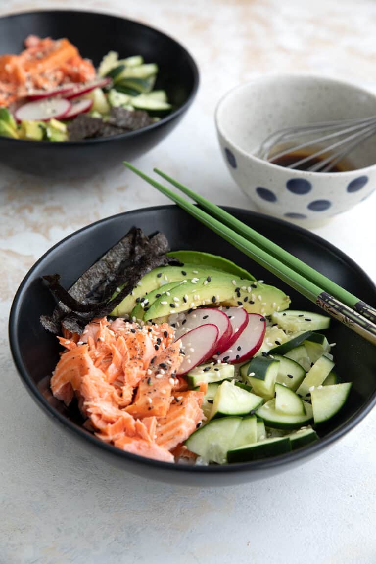 Two Keto Sushi Bowls in black bowls on a concrete table.